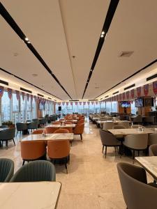 a dining room with tables and chairs and windows at Mora by jodna - فندق مورا in Al Khobar