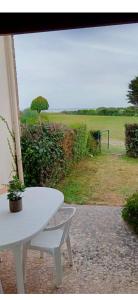 a white table and chair with a view of a field at Studio les pieds dans l eau in Sarzeau