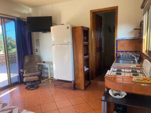 a kitchen with a refrigerator and a table and a chair at Casitas Las Palmas - Brisa Marina in Punta Mita