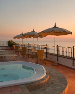 a patio with a hot tub and umbrellas at Hotel Nettuno in Forio d'Ischia