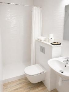 a white bathroom with a toilet and a sink at Gościniec Piast Pokoje i Camper Park in Brzeźno +53 photos