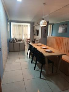 a dining room and living room with a table and chairs at Apartamento 1 km da praia com ar e garagem in Vila Velha