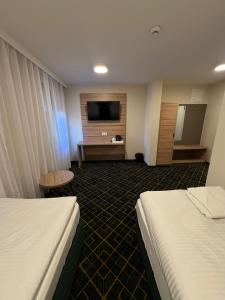 a hotel room with two beds and a flat screen tv at Royal Apartamenty in Bytom