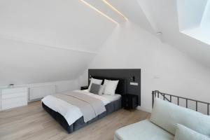 a white bedroom with a bed and a couch at Kaisers Nescht in Vogtsburg