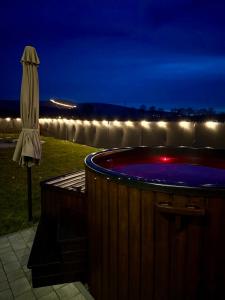 an umbrella and a hot tub at night with a waterfall at Pod Izerskim Niebem - kameralny domek z balią, w sąsiedztwie Świeradowa-Zdroju in Mroczkowice