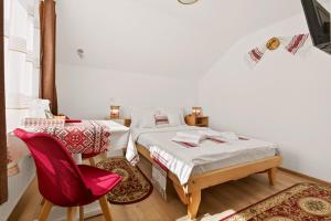 a bedroom with two beds and a red chair at Casa Dava in Râşnov