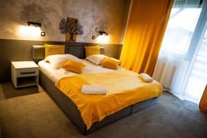 a bedroom with a large bed with yellow sheets and pillows at Conca Verde Râșnov in Râşnov +22 photos