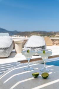 two martini glasses sitting on a table next to a pool at Hilltop Suites Milos in Mytakas