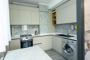 a kitchen with white cabinets and a washing machine at Apartaments Miro in Chişinău +3 photos