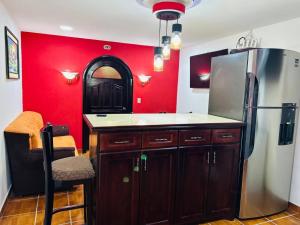 a kitchen with a refrigerator and a red wall at El Tesoro de Arturo in Tilapa