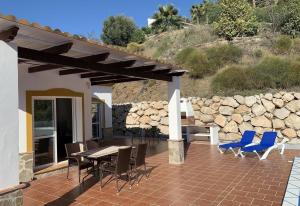a patio with a table and chairs and a stone wall at Casa Verdejo in Cómpeta