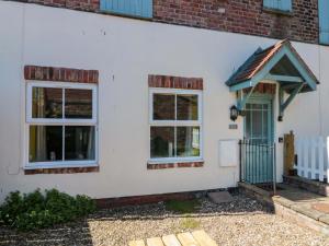 a white house with a blue door and windows at Farriers Cottage in Bridlington