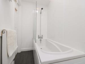 a white bathroom with a tub and a shower at Farriers Cottage in Bridlington +10 photos