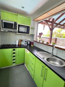 a green kitchen with a sink and a window at Lili bungalows in Capesterre