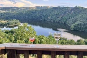two glasses of wine sitting on a wooden railing with a river at Yourte en bord Loire avec plage privée in Saint-Jean-Saint-Maurice-sur-Loire +11 photos