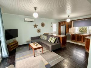 a living room with a couch and a tv at Pico Island Villas 117 - Natural Pools and Incredible Views in São Roque do Pico