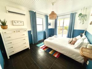 a bedroom with a bed and a dresser and a window at Pico Island Villas 117 - Natural Pools and Incredible Views in São Roque do Pico