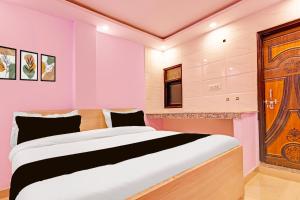 a bedroom with a large bed and a wooden door at Hotel O Sky House Residency in New Delhi