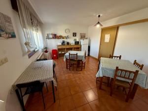 a living room with two tables and chairs and a kitchen at Pensión Codesal in O Pedrouzo