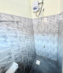 a bathroom with a shower with a tiled wall at Biez Homestay in Karatu