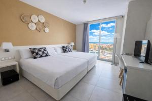 a bedroom with a large white bed and a television at Palladium Hotel Peñiscola in Peniscola