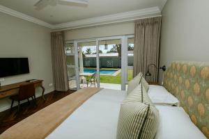 a bedroom with a bed and a desk and a television at Highlands House in Harare