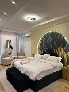 a bedroom with a large bed with a painting on the wall at Vluxuries in Lekki
