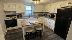 a kitchen with white cabinets and a black refrigerator at Cozy Mountain Rancher in Harpers Ferry