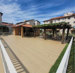 an outdoor patio with a pergola and tables and chairs at Apê mar e descanso com piscina no VOG JOÃO DE GOES ILHÉUS BA in Ilhéus
