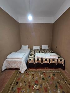 two beds in a small room with a rug at Dunes Activity Camp in Mhamid