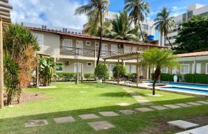 a courtyard of a building with a swimming pool and palm trees at Pousada das Araras in Maceió