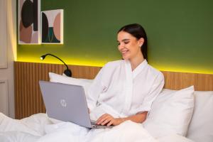 a woman sitting in bed using a laptop computer at Blue Tree Towers Millenium Porto Alegre in Porto Alegre