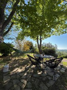 a patio with a table and chairs under a tree at Prana Hill in Cupramontana