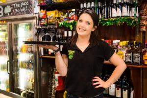 a woman standing in a bar holding a tray of wine glasses at Boorowa Hotel in Boorowa