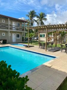 a swimming pool with a pergola next to a house at Pousada das Araras in Maceió