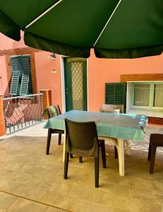 a table and chairs under a green umbrella on a patio at Casetta n.2 con piscina in Sarola