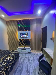 a bedroom with a bed and a tv on a wall at Asika Luxe Living in Ayobo