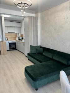 a living room with a green couch and a kitchen at TheBlueEscape Apartment in Năvodari