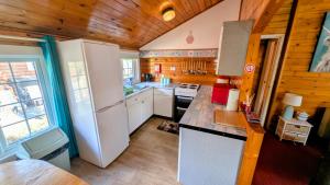 a kitchen with white appliances and wooden walls at Cabin Gezellig in Trawsfynydd