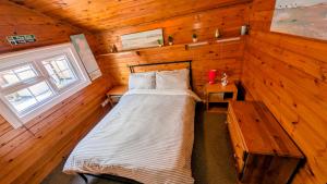 a bedroom with a bed and a wooden wall at Cabin Gezellig in Trawsfynydd