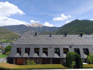 a house with a roof with mountains in the background at SUITEDREAMS - Camp de Baix in La Massana