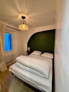 a bedroom with a large white bed with a green headboard at L'Escale Auffan - Mourillon in Toulon