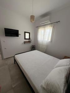 a white bedroom with a bed and a tv at NAXIAN OLIVE House in Glinado Naxos