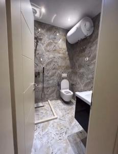 a bathroom with a toilet and a stone wall at Helix Apartments in Fier +11 photos