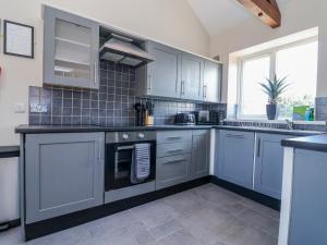 a kitchen with blue cabinets and a stove top oven at Elwy Cottage in St Asaph +30 photos