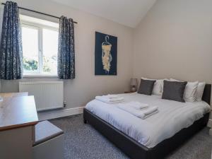 a bedroom with a large white bed with a window at Elwy Cottage in St Asaph