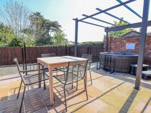 a patio with a table and chairs and a hot tub at Elwy Cottage in St Asaph