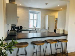 a kitchen with a counter with stools in it at Trearddur View in Holyhead