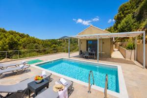 a swimming pool with a patio and a house at Villa Angela in Trapezaki