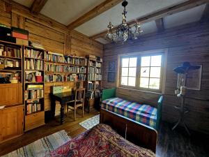 a room with a library with a desk and a window at Gałęziówka, Doły Biskupie in Kunów